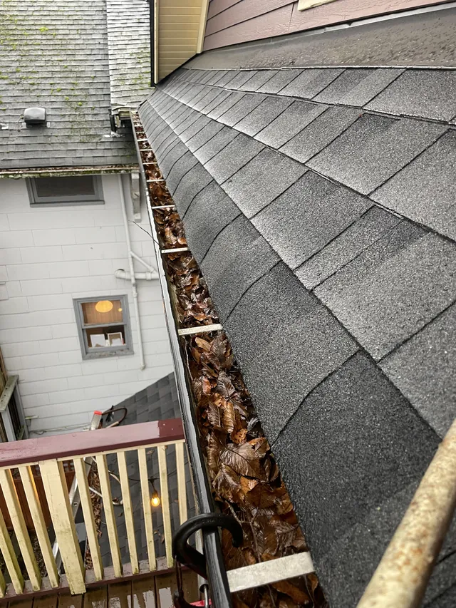 Gutter channel filled with leaves before cleaning.