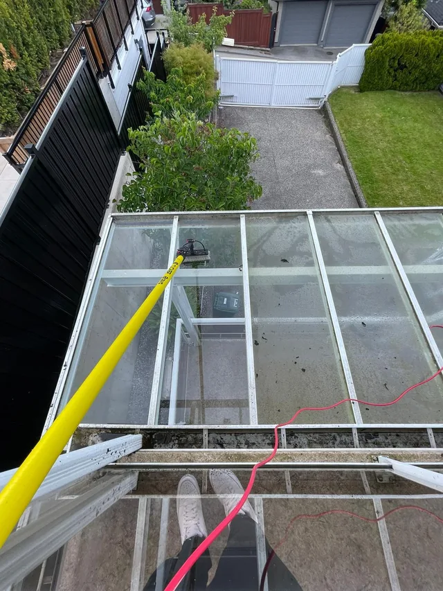 Cleaning pole reaching across a glass canopy; work in progress.