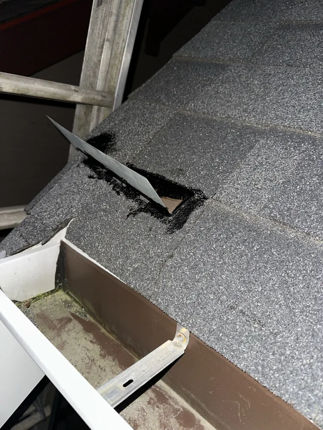 Small metal diverter secured across the shingle surface near the gutter.